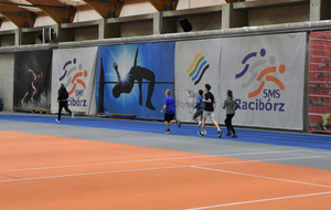 Osoby biegną na hali sportowej 