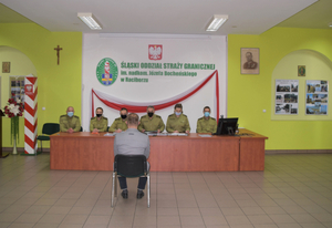 Osoba siedzi na krześle przed komisją egzaminacyjną 