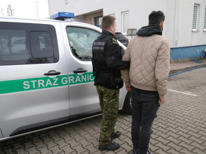 Funkcjonariusz Straży Granicznej prowadzi zatrzymanego obywatela Algierii 
