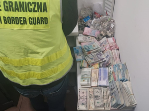 Funkcjonariusz SG stoi przy stoliku na którym leżą pieniądze Funkcjonariusz SG stoi przy stoliku na którym leżą pieniądze
