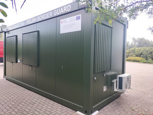 Mobilny kontener biurowy koloru zielonego. Na lewym boku na samej górze napis Straż Graniczna - Polish Border Guard. Mobilny kontener biurowy koloru zielonego. Na lewym boku na samej górze napis Straż Graniczna - Polish Border Guard.