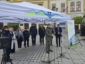  Namiot z napisem &quot;Miasto Żywiec&quot;, przy mikrofonie komendant SG w Bielsku-Białej ppłk SG Paweł Zoń.