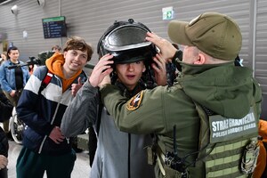 Funkcjonariusz SG pomaga założyć strój pirotechnika jednemu z uczestników