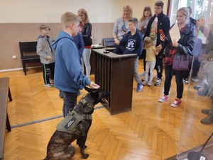  Jeden z uczestników kładzie dłoń na głowie psa. Inne osoby się przyglądają.