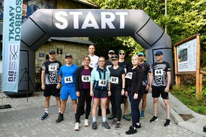  Uczestnicy biegu stojący pod balonem z napisem start.