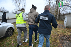  Funkcjonariusze Straży Granicznej prowadza osobę