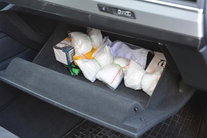  Otwarty schowek samochodu. Pudełka, smycz i cztery woreczki strunowe z zawartością.