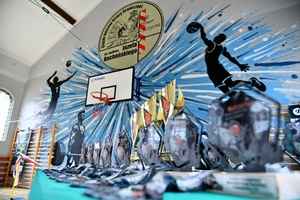 Stół z medalami i pucharami w tle mural.