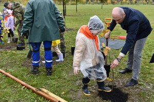  Łukasz Sowada i przedszkolak sadzą drzewo.
