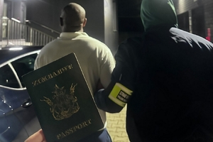  Paszport z napisem Zimbabwe. Osoba zatrzymana jest prowadzona przez Funkcjonariusza Straży Granicznej.