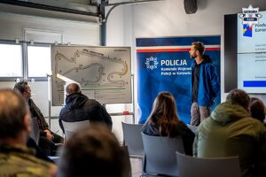 Osoba omawiająca plansze z torem wyścigowym